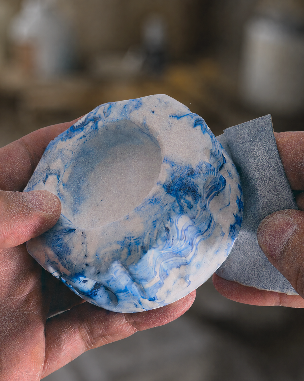Hands sanding an Aegean Blue marbled bowl by hand in the workshop